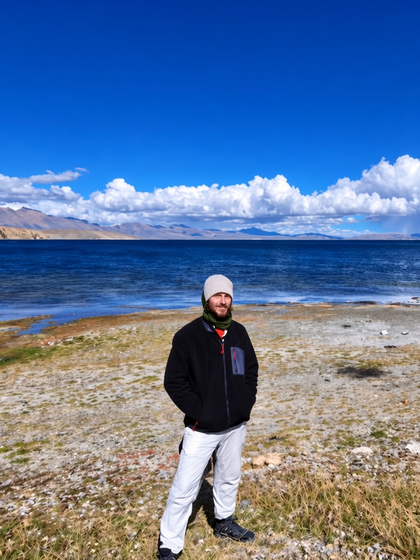 Daniel James Duncan beside a high blue lake, March 2026.